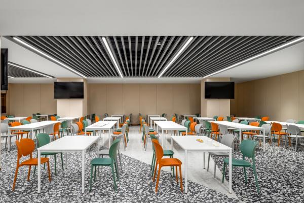 企业员工餐厅家具案例，白色方形餐桌配橙色和绿色餐椅，空间宽敞明亮，适合员工用餐、休闲与团队交流